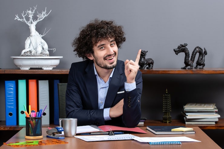 front-view-curly-hair-businessman-surprising-with-idea-sitting-desk-modern-office_140725-94960